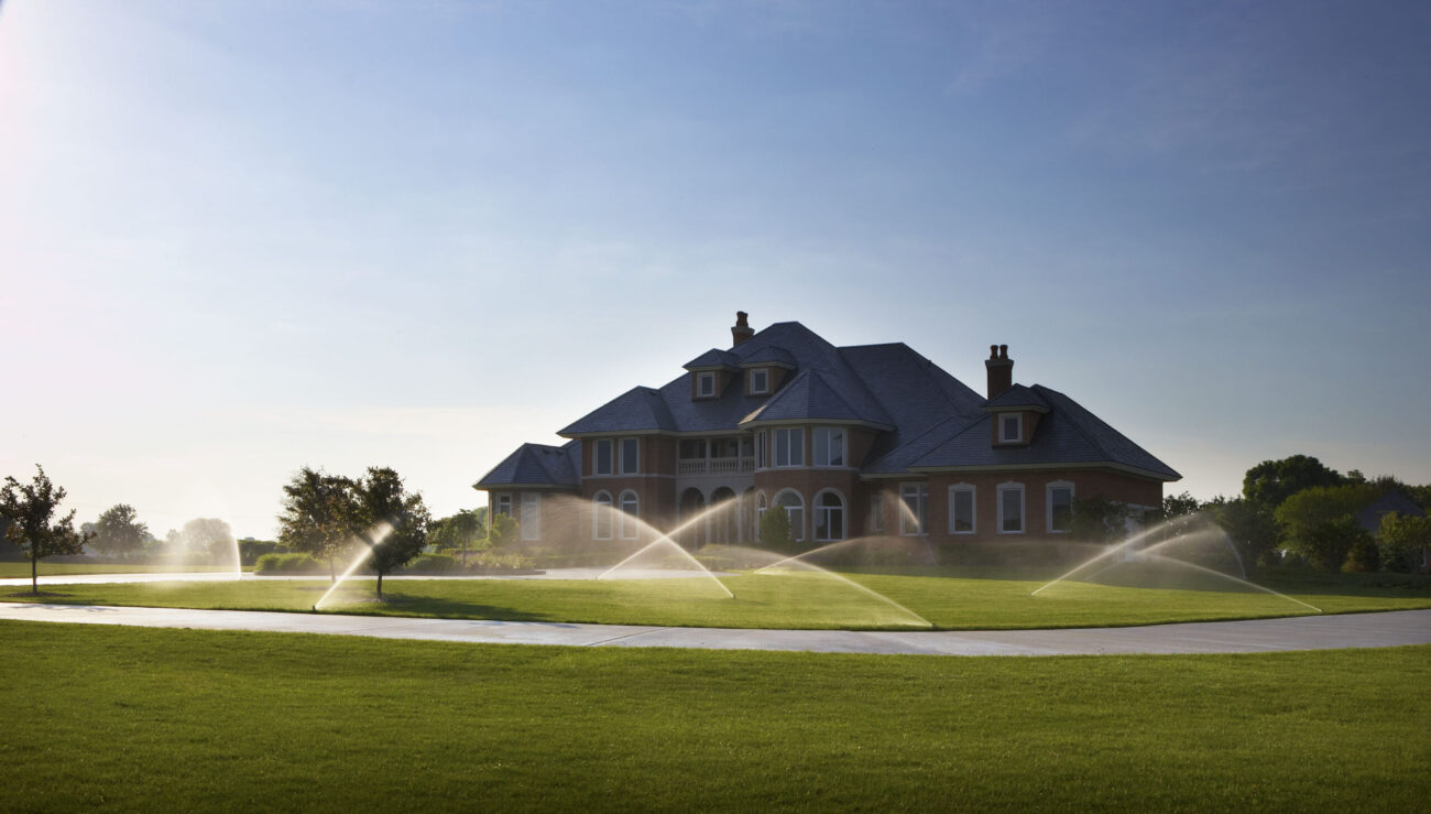 Sprinkler system watering a lush lawn at a Utah County home